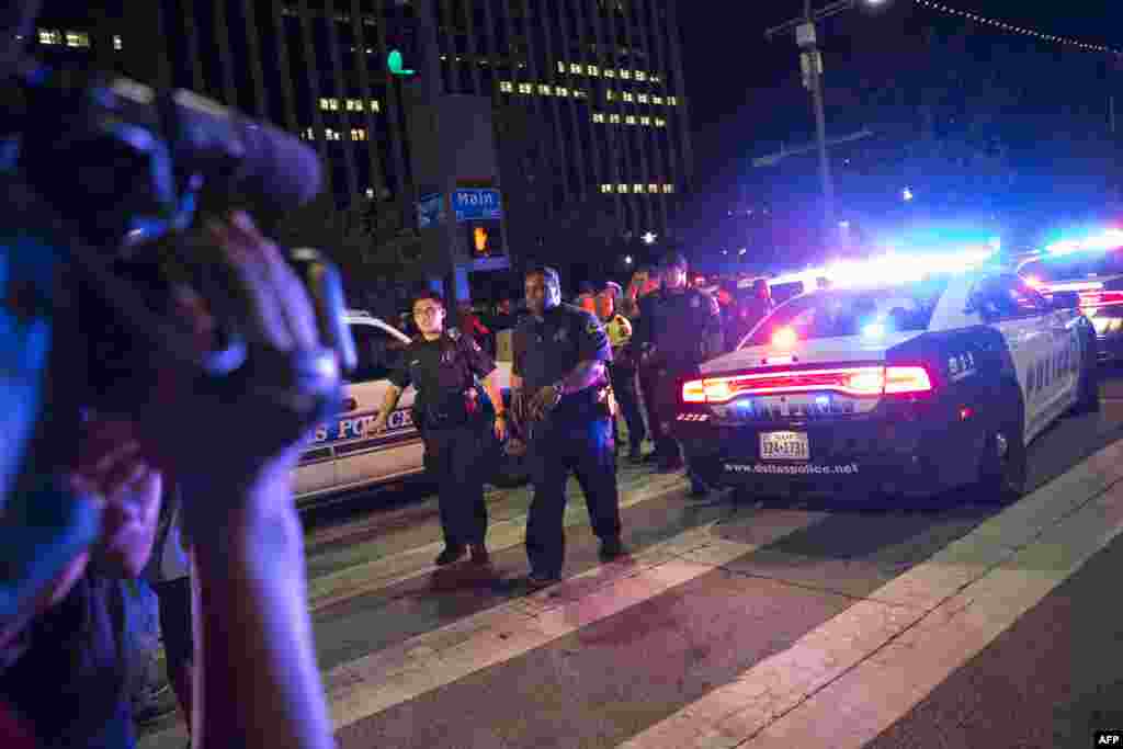 Bystanders stand near pollice baracades following the sniper shooting in Dallas on July 7, 2016. 