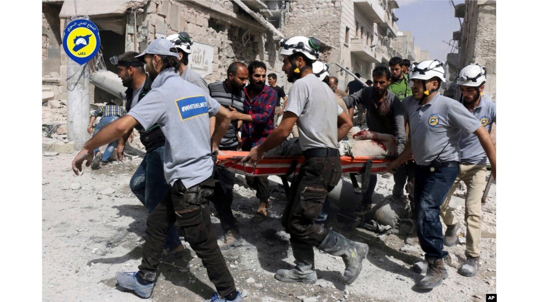 FILE - In this Sept. 21, 2016, file photo, provided by the Syrian Civil Defense White Helmets, rescue crews work the site of airstrikes in the al-Sakhour neighborhood of the rebel-held part of eastern Aleppo, Syria.