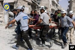 FILE - In this Wednesday, Sept. 21, 2016, file photo, provided by the Syrian Civil Defense White Helmets, rescue crews work the site of airstrikes in the al-Sakhour neighborhood of the rebel-held part of eastern Aleppo, Syria.