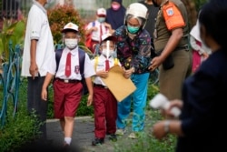 Siswa yang mengenakan masker tiba di hari pertama pembukaan sekolah kembali di Jakarta, Senin, 30 Agustus 2021. (Foto: AP)