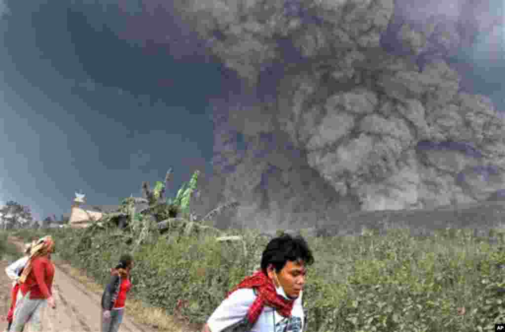 Villagers flee as Mount Sinabung releases pyroclastic flows during an eruption in Namantaran, North Sumatra, Feb. 1, 2014.
