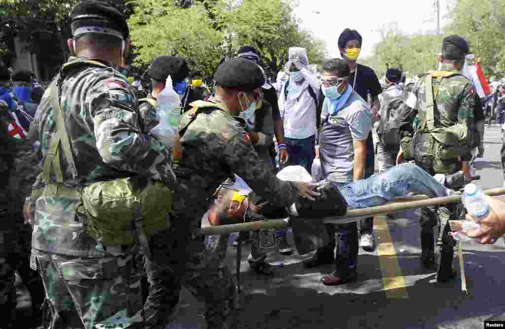 A military medical unit team assists an injured protester after riot police threw a tear gas canister during clashes in Bangkok, Dec. 2, 2013. 