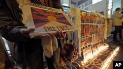 A protester holds a placard next to a Free Tibet candlelit display showing the pictures of Tibetans who died of self-immolation, in front of the Liaison Office of the Central People's Government in the Hong Kong Special Administrative Region, February 22,