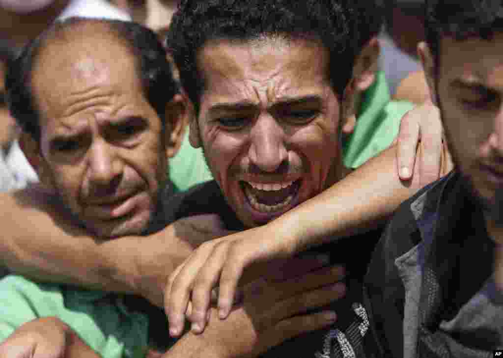 A relative bursts into tears while mourners try to comfort him as they gather around the bodies of seven members of the Kelani family, killed overnight by an Israeli strike in Gaza City, in Beit Lahiya, northern Gaza Strip, July 22, 2014.
