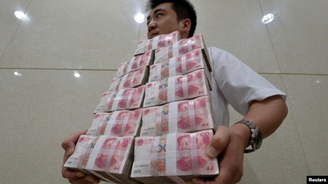 中国山西太原一家银行职员手捧成捆的人民币百元现钞。（资料照片）