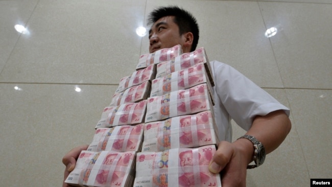 中国山西太原一家银行职员手捧成捆的人民币百元现钞。(资料照片)