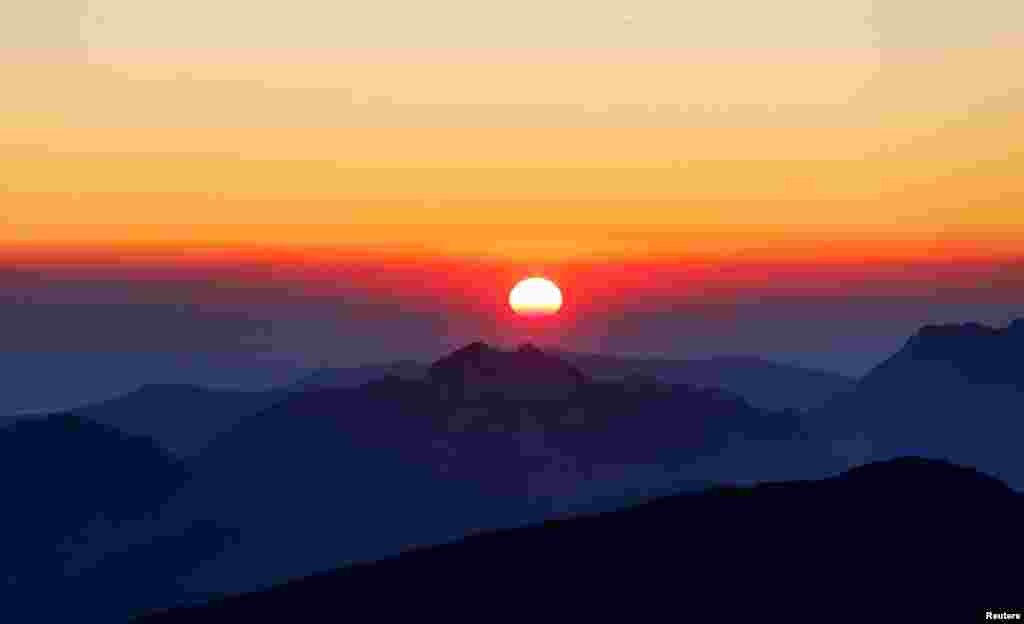The sunrise is seen from the peak of the Kaiser Mountains on a summer day in Ellmau, Austria.