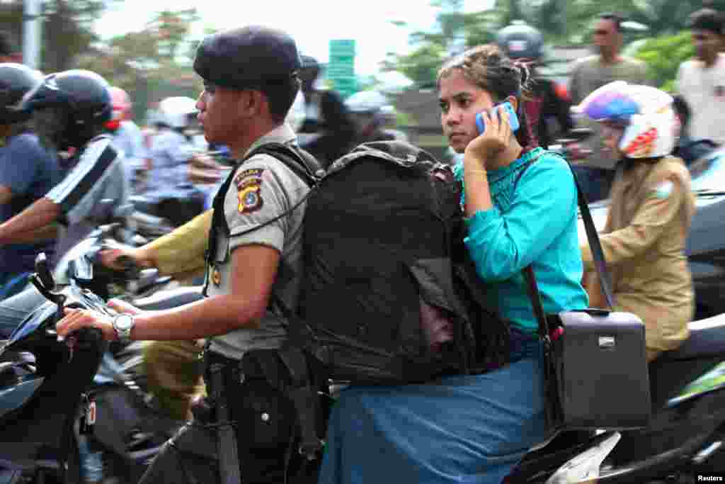 A police evacuates his wife in a motorcycle in Banda Aceh. (Reuters)