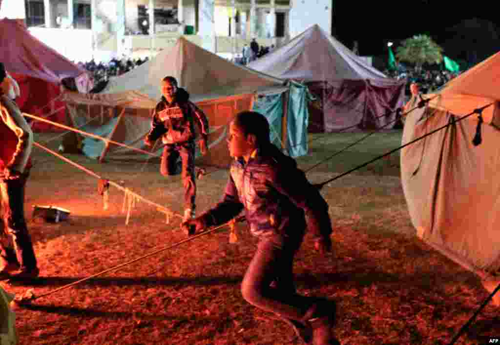 March 31: Libyans loyal Muammar Gaddafi run after journalists as they pass tents set up in Bab Al-Aziziyah, Gaddafi's heavily fortified compound in Tripoli. (Reuters/Zohra Bensemra)