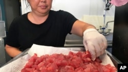 This Tuesday, April 16, 2019 photo shows Michele Miyanaga preparing cubes of raw ahi, or tuna, at Aloha Poke Shop, a store in Honolulu, Hawaii. (AP Photo/Audrey McAvoy)