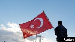 Un homme tient un drapeau turc lors du 38e marathon d'Istanbul, Turquie, le 13 novembre 2016.