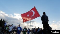 Un homme tient un drapeau turc lors du 38e marathon d'Istanbul, Turquie, le 13 novembre 2016.
