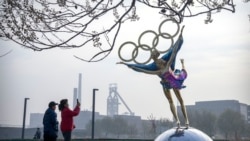 بیجنگ میں لوگ اولمپکس کی منتظم کمیٹی کے دفتر کے باہر بنے ایک مجسمے کی تصویر بنا رہے ہیں