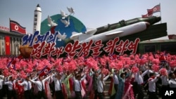 북한이 김일성 주석의 105번째 생일(태양절)을 맞아 15일 평양 김일성광장에서 대규모 열병식을 개최했다. 북한 주민들이 인공기와 꽃술을 들고 행진하고 있다.