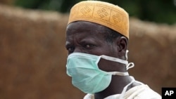 A local health worker wears a mask as he removes earth contaminated by lead from a family compound in the village of Dareta in Gusau, Nigeria, June 10, 2010.