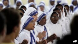 FILE - Nuns of the Missionaries of Charity pray near the tomb of Mother Teresa during a mass on her birth anniversary in Kolkata, India, August 26, 2015.