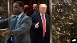 President-elect Donald Trump gestures as he arrives in the lobby of Trump Tower in New York, Dec. 6, 2016, to speak to members of the media. 