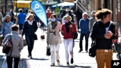 People walk in a shopping street in Gelsenkirchen, Germany, as many smaller stores are allowed to open on Monday, April 20, 2020. (AP Photo/Martin Meissner)