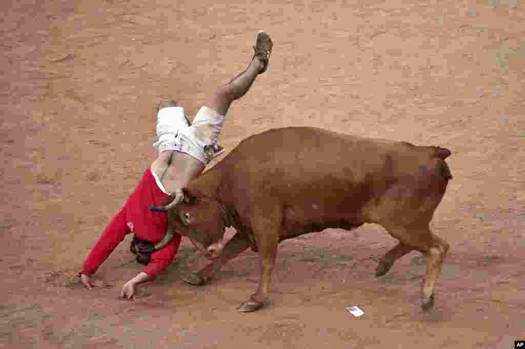 A reveler jumps over a bull following the running of the bulls at the San Fermin Festival in Pamplona, Spain.
