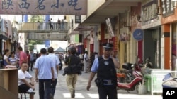 A policeman talks on his mobile as he patrols near the site of Sunday's attack in Kashgar in China's far western Xinjiang Uygur Autonomous Region, Tuesday, Aug. 2, 2011.