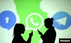 Silhouettes of mobile users are seen next to logos of social media apps Signal, Whatsapp and Telegram projected on a screen in this picture illustration taken March 28, 2018.