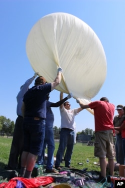 Students and faculty, including Mark Iewicz, center, a mechanical engineering student, prepare to test launch a camera-carrying balloon at the University of Hartford in West Hartford, Connecticut, Aug. 9, 2017.