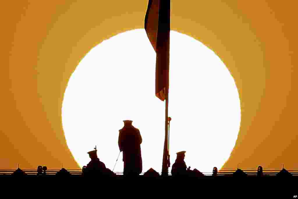 Chinese paramilitary policemen watch over Tiananmen Square from a rooftop across from the Great Hall of the People druing the sunrise in Beijing.