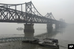 FILE - Trucks move across the bridge linking North Korea with the Chinese border city of Dandong in this March 3, 2016 photo.