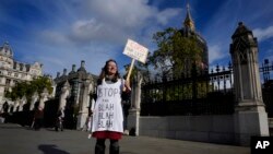 A lone climate demonstrator holds a banner outside parliament in London, Oct. 25, 2021, ahead of the UN climate conference COP26 that will be held in Glasgow, Scotland.