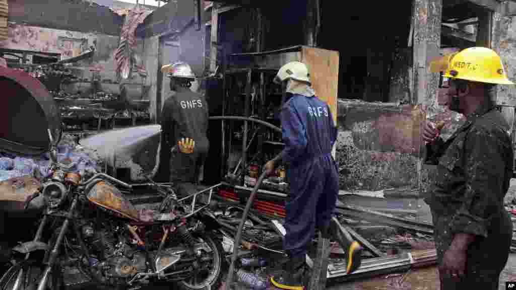 Bombeiros pulverizam água sobre as remanescentes de um posto de gasolina depois de uma explosão em Acra, Gana, Quinta-feira, 4 de Junho, 2015.