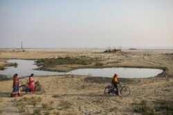 Orang-orang berjalan di sebidang tanah kering yang dulunya adalah sebuah desa di Pulau Sagar, salah satu pulau yang membentuk Sundarbans, wilayah delta dataran rendah dengan sekitar 200 pulau di Teluk Bengal, India, Selasa, Jan 14, 2020. (Foto: dok).