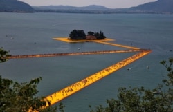 FILE - People walk on the installation 'The Floating Piers' by Christo near Sulzano, northern Italy, July 2, 2016. (REUTERS/Wolfgang Rattay/File Photo)