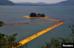 FILE - People walk on the installation 'The Floating Piers' by Christo near Sulzano, northern Italy, July 2, 2016. (REUTERS/Wolfgang Rattay/File Photo)