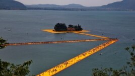 FILE - People walk on the installation 'The Floating Piers' by Christo near Sulzano, northern Italy, July 2, 2016. (REUTERS/Wolfgang Rattay/File Photo)