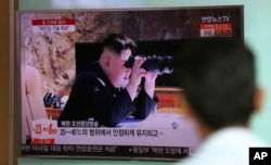 FILE - A man watches a TV screen showing a local news program reporting about North Korea's missile firing with an image of North Korean leader Kim Jong Un with a pair of binoculars, at Seoul Train Station in Seoul, South Korea, July 5, 2017.