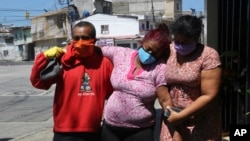 Mariela Jácome (derecha) ayuda a su madre Catherine Quiñonez (centro), de camino al hospital en Guayaquil, Ecuador. La mujer presentó síntomas de coronavirius el 16 de abril de 2020.