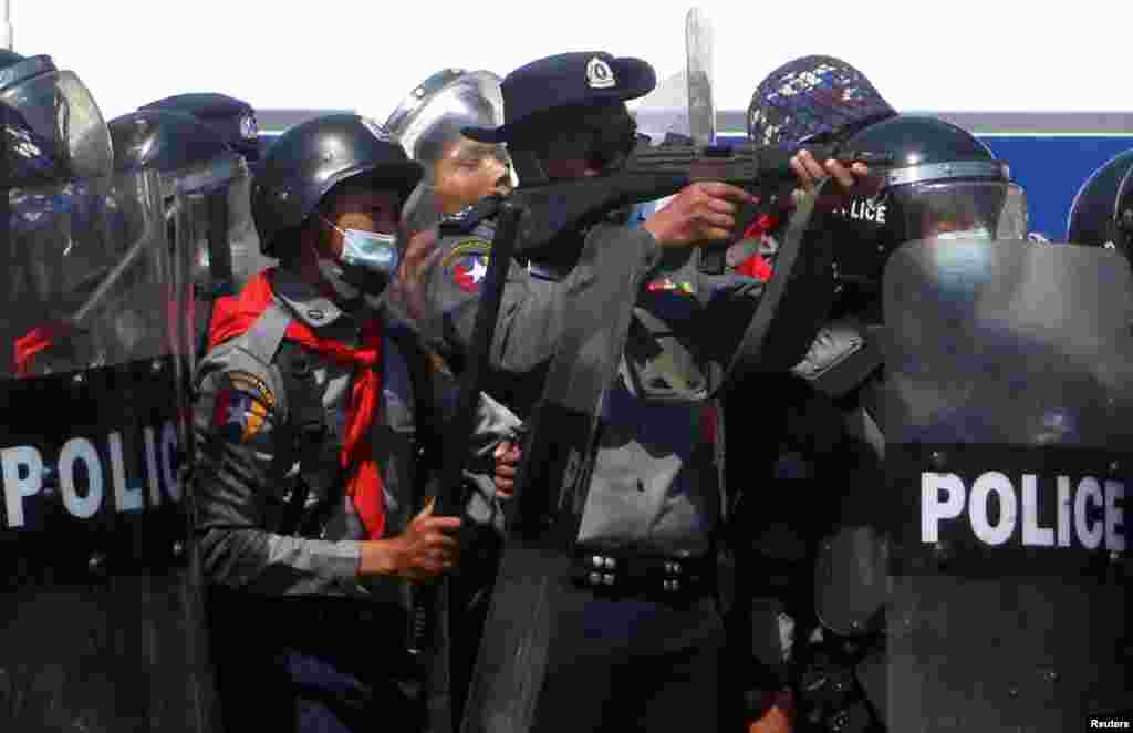 A police officer holds a weapon during clashes with protesters rallying against the military coup and demanding the release of elected leader Aung San Suu Kyi, in Naypyitaw, Myanmar.