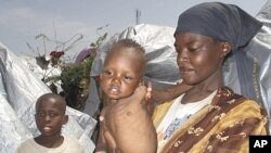 An Somali woman and her children displaced by famine, wait to receive food aid near their makeshift shelters in Mogadishu, Somalia, Friday, July 22, 2011
