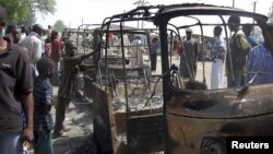 Residents survey vehicles damaged after a bomb blast at a primary school in Maiduguri, the capital of Nigeria's Borno state, February 29, 2012. 