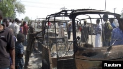 Residents survey vehicles damaged after a bomb blast at a primary school in Maiduguri, capital of Borno state, February 29, 2012.