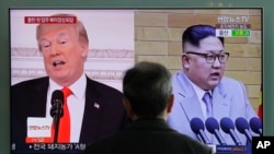 FILE - A man watches a TV screen showing file footages of U.S. President Donald Trump, left, and North Korean leader Kim Jong Un during a news program at the Seoul Railway Station in Seoul, South Korea, March 27, 2018.