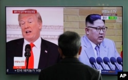 FILE - A man watches a TV screen showing file footage of U.S. President Donald Trump and North Korean leader Kim Jong Un during a news program at the Seoul Railway Station in Seoul, South Korea, March 27, 2018.