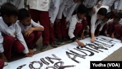 Aksi mengumpulkan uang receh berbentuk koin di lembaran spanduk bertuliskan "Coin untuk Australia" di Kompleks Gelanggang Olah raga Manahan, Senin siang (23/2). (Foto: VOA/Yudha)