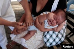 Seorang ibu memeluk bayinya saat pemberian imunisasi di Managua,15 April 2013.