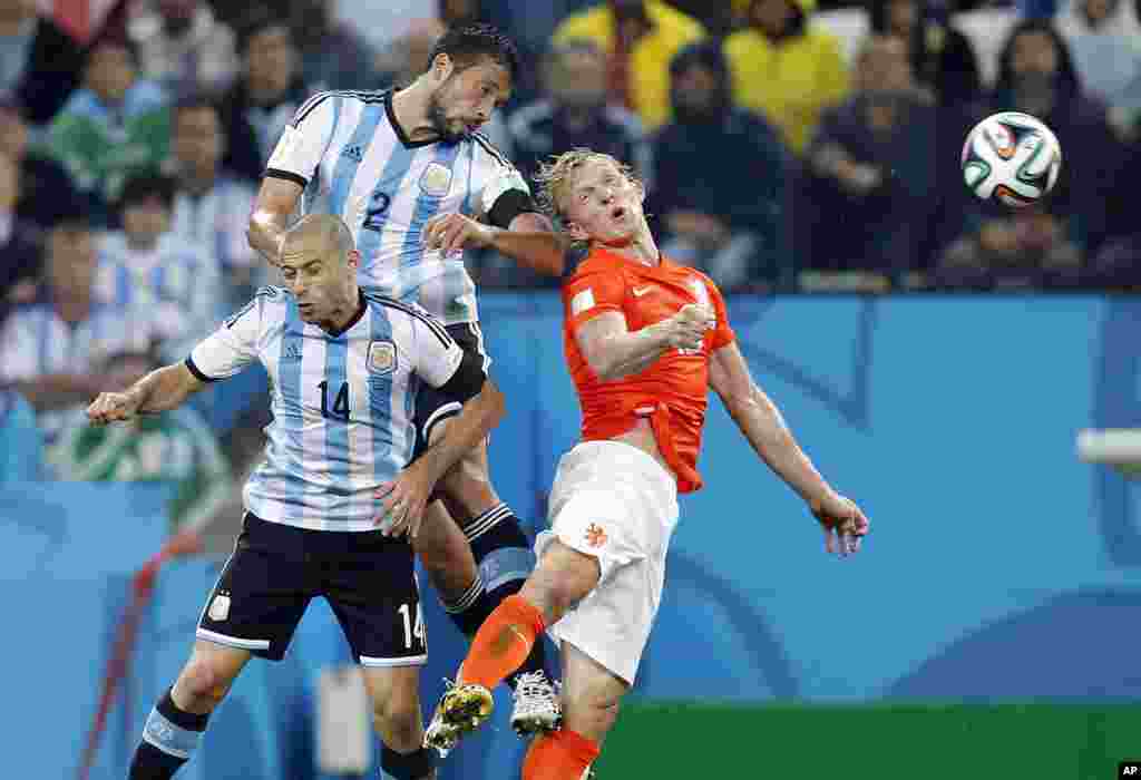 Netherlands' Dirk Kuyt goes for a header with Argentina's Javier Mascherano and Ezequiel Garay during the World Cup semifinal soccer match at the Itaquerao Stadium in Sao Paulo, Brazil, July 9, 2014. 
