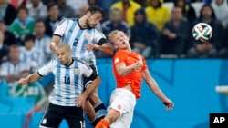 Netherlands' Dirk Kuyt goes for a header with Argentina's Javier Mascherano and Ezequiel Garay during the World Cup semifinal soccer match in Sao Paulo, Brazil, July 2014. (AP Photo/Frank Augstein)