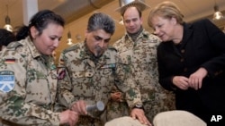 In a picture provided by the press department of German Government, German soldiers show off an 'Afghan fridge' made of mud and straw to keep grapes fresh to German Chancellor Angela Merkel in Kunduz, Afghanistan, 18 Dec 2010