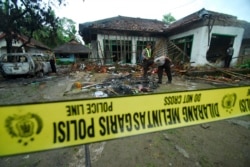 Polisi memeriksa rumah pengikut Ahmadiyah yang rusak setelah diserang sekelompok orang di Pandeglang, Banten, 7 Februari 2011. (Foto: AP)