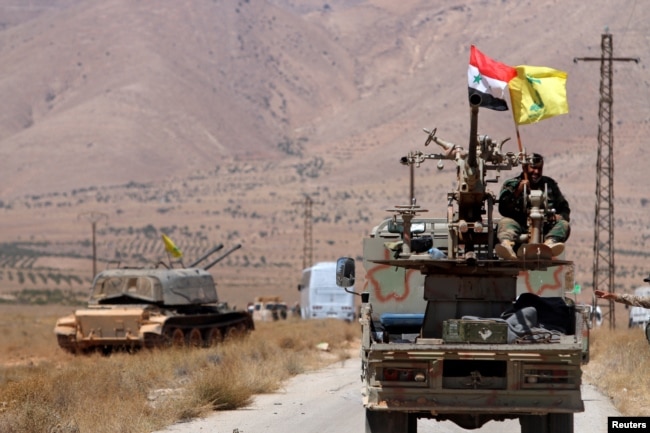 FILE - Hezbollah and Syrian flags flutter on a military vehicle in Western Qalamoun, Syria, Aug, 28, 2017.