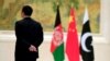 FILE - A member of the security personnel stands guard next to, from left, Afghan, Chinese and Pakistani flags during the first China-Afghanistan-Pakistan Foreign Ministers' Dialogue in Beijing, China, Dec. 26, 2017. 